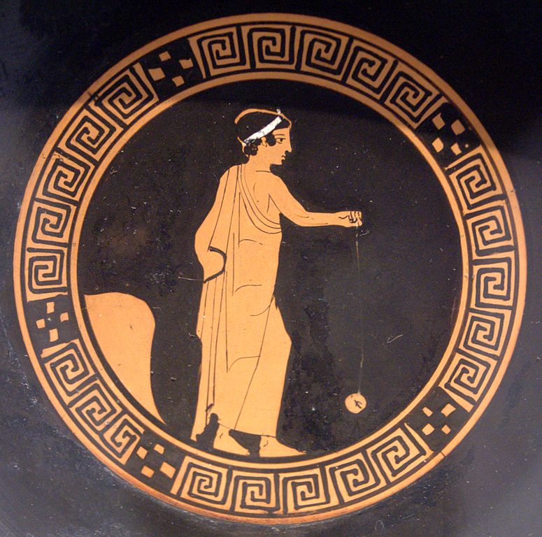 The bottom of the greek pottery called kylix, painted in red-figure style, depicting a boy playing yo-yo.