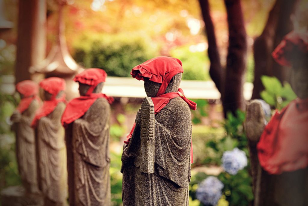 Jizo bodhisattva stone statues with read hats are standing along the road