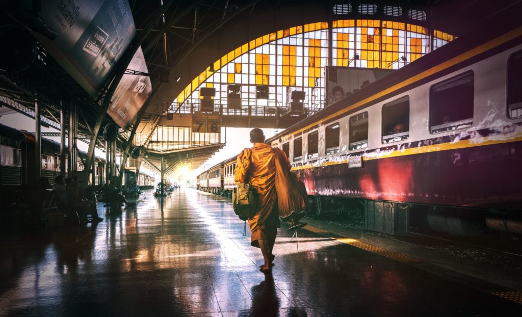 A Buddhist monk walks through Bangkok’s old train station to catch his departure.