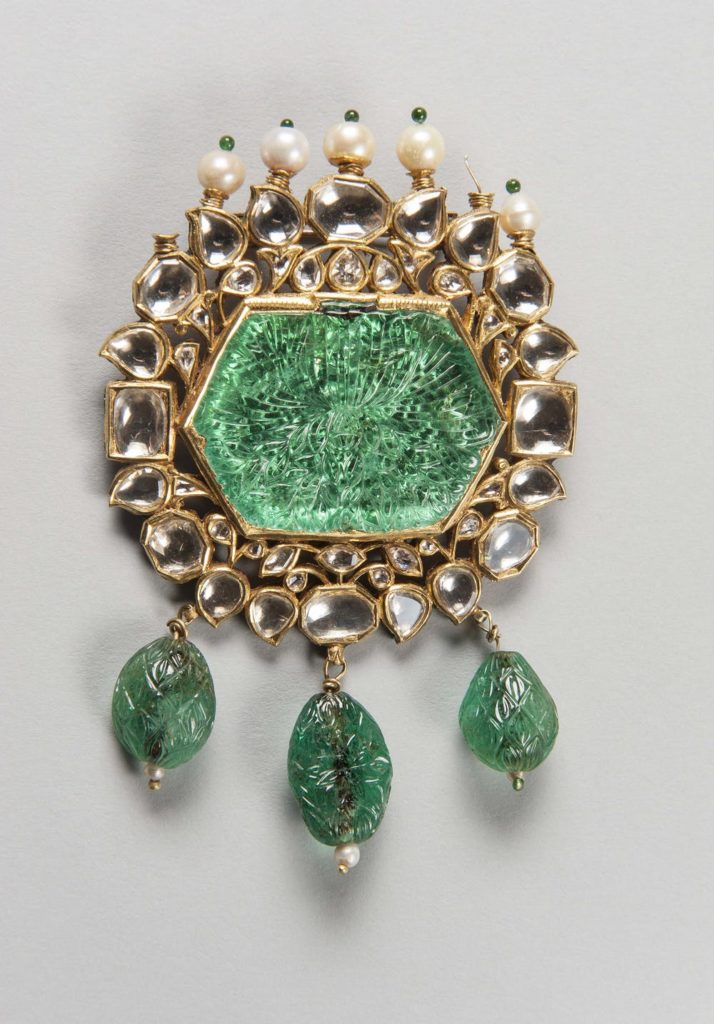 unique emerald jewelry: kundan gold brooch with emerald center stone and dangling carved emeralds 