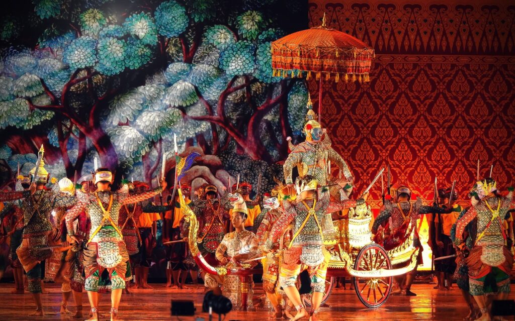 The khon (Thai masked dance drama performance), one man on the couch with the parasol, a group of men in the scene appear around the main character