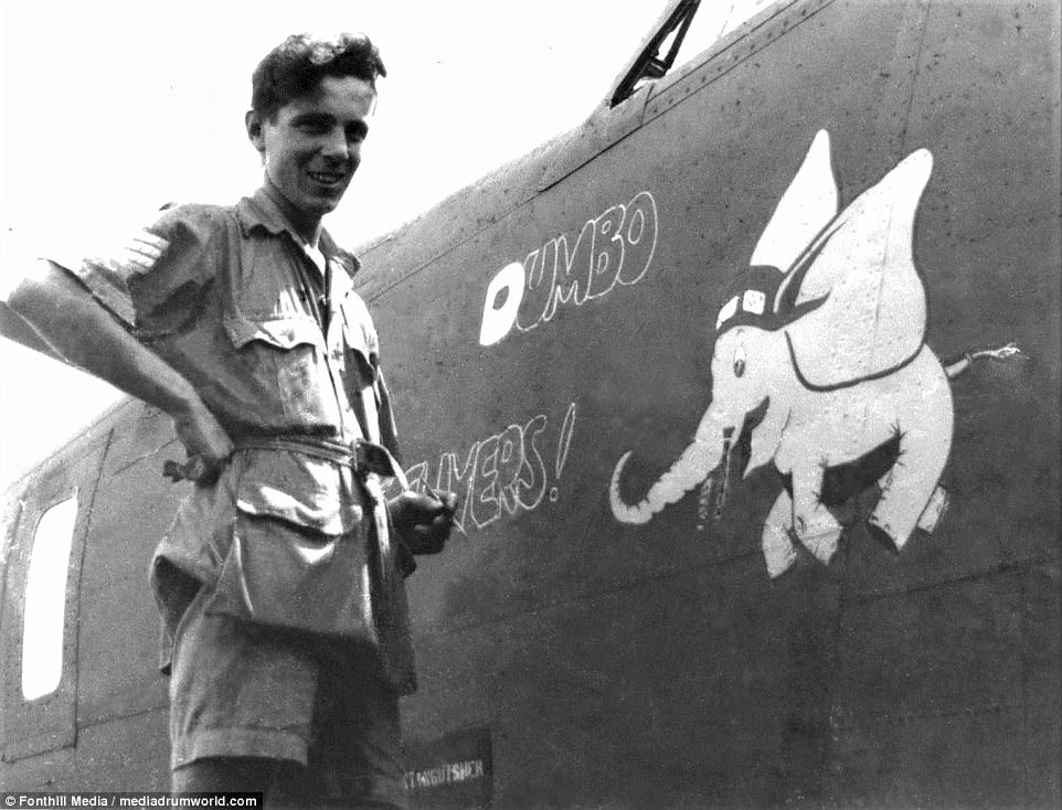 Air gunner Bill Kirkness during the painting of his "Dumbo Delivers!" Nose Art design on the forward fuselage of B839, a Mk III Liberator at Salbani, 1943.