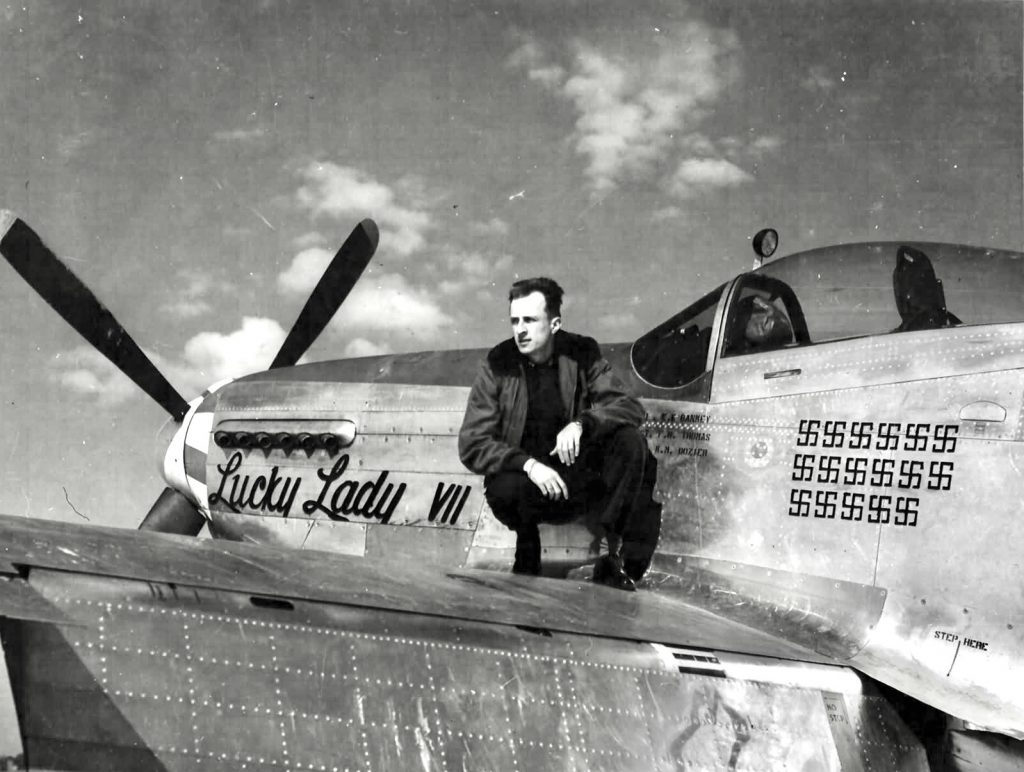 nose art by pilots: Major Ernest Bankey posing on the wing of his P-51 Mustang with "Lucky Lady VII" painting.