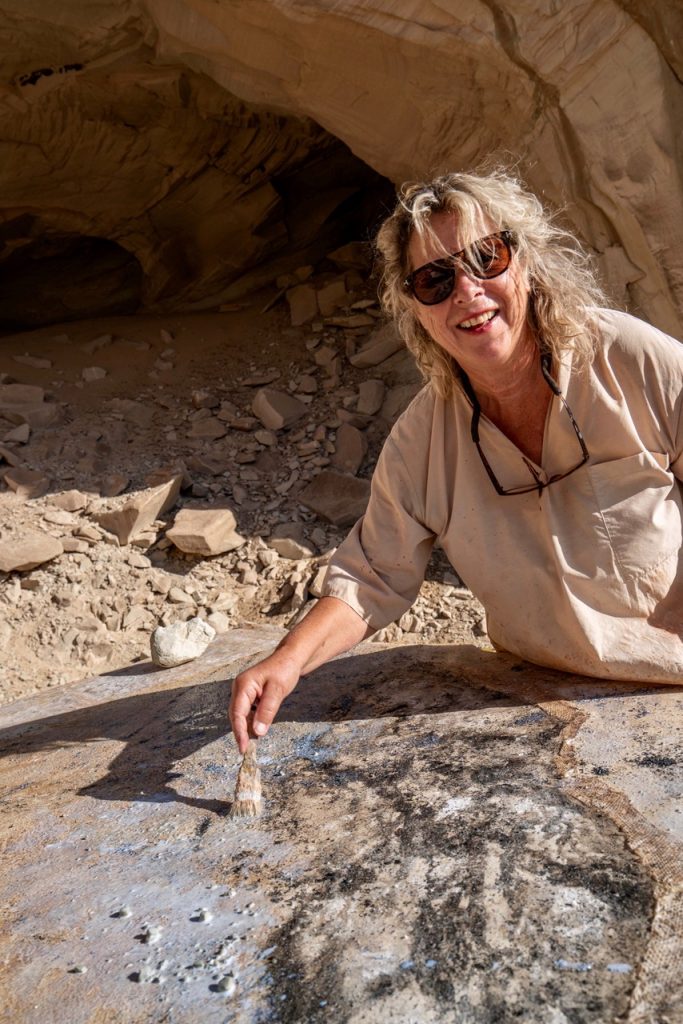 Ulrike Arnold painting with earth, meteorite dust and snakeskin in front of Broken Arrow Cave, Utah, 