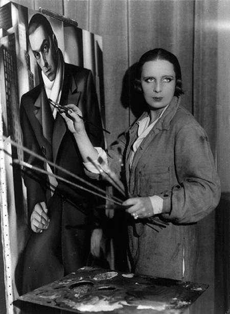 Marisa de Lempicka: Black and white photograph of a white woman painting at an easel, wearing an artist's smock. Her hair is perfect, as is her make up. She looks past the camera. On the easel is a portrait of the artist's husband. Tamara de Lempicka painting her husband Tadeusz Lempicki, 1923.