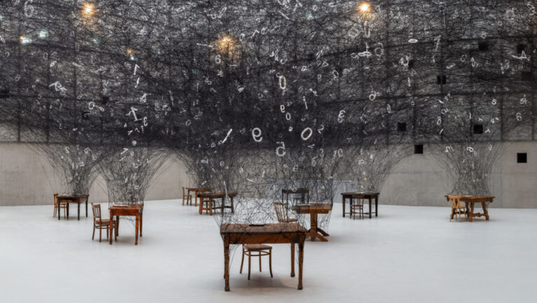 Counting Memories Chiharu Shiota: Counting Memories, Installation: wooden desks, chairs, paper, black wool, Silesian Museum, Katowice, Poland. Photo: Sonia Szeląg. 2019.
