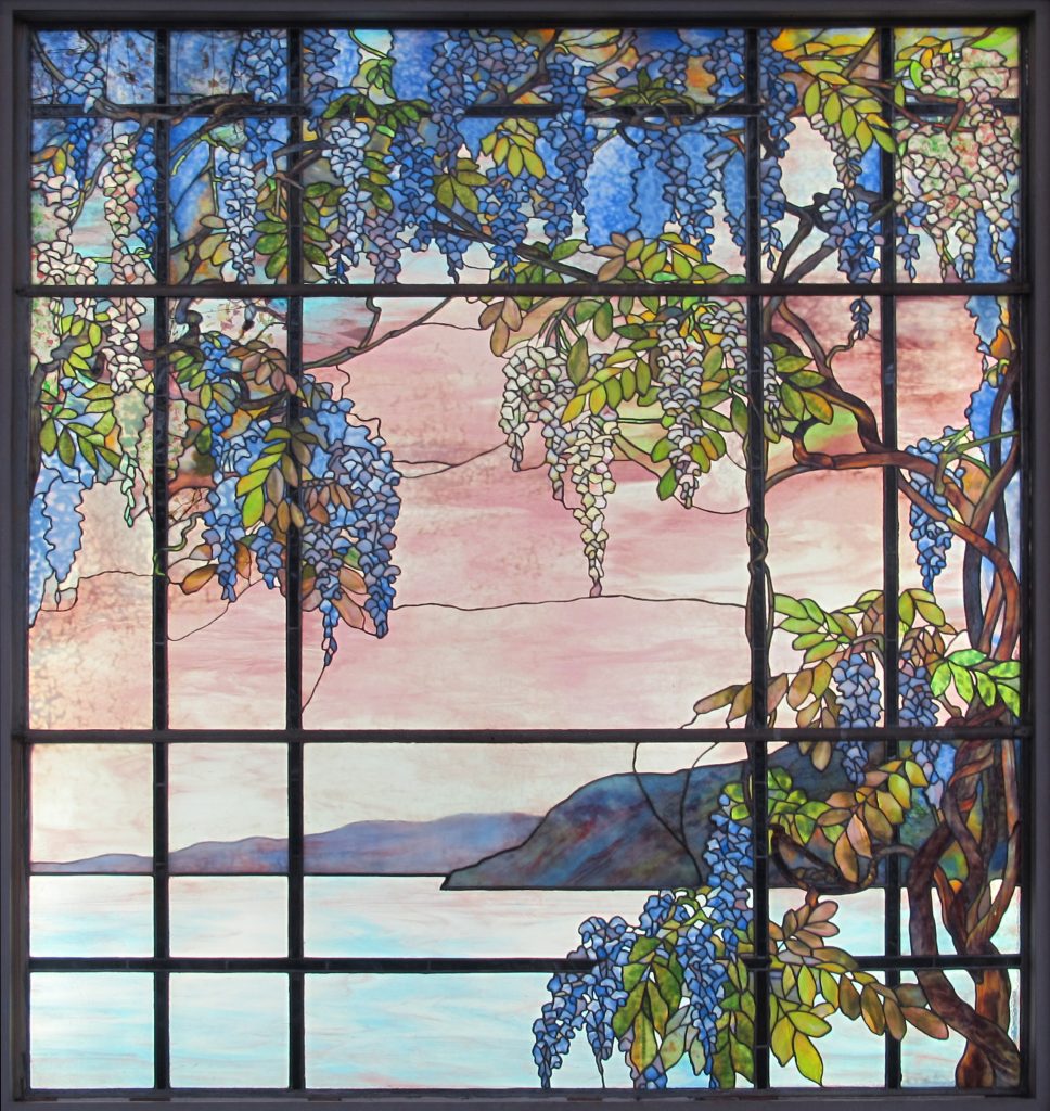Tiffany's Glass window depicting vines framing a waterscape with mountains in the background.