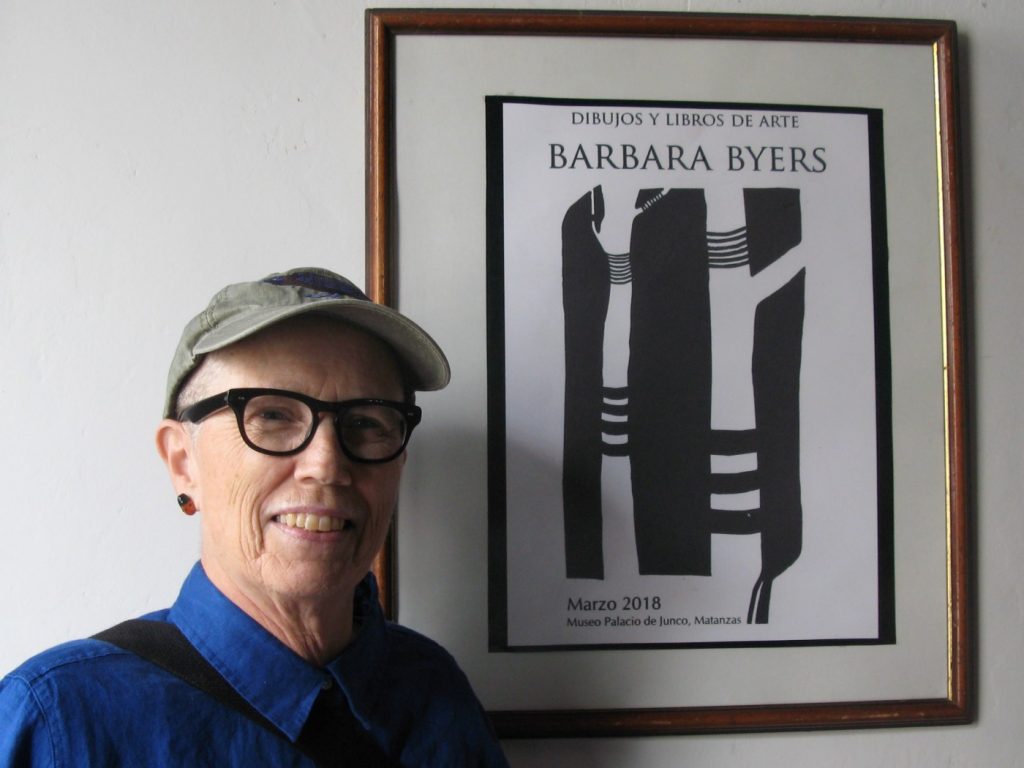 Margaret Randall: Artist Barbara Byers with a poster for her show at Museo Palacia de Junco in Matanzas, Cuba, 2018. Medium.
