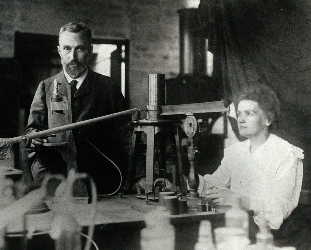 Marie Curie portraits: Marie and Pierre Curie in the laboratory, c. 1904. Wikimedia Commons (public domain).
