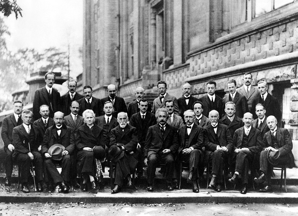 Marie Curie portraits: Benjamin Couprie, 1927 Solvay Conference on Quantum Mechanics, 1927. Wikimedia Commons (public domain).
