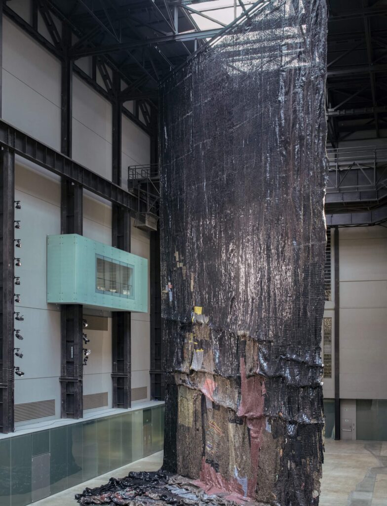 El Anatsui Turbine Hall: El Anatsui, Behind the Red Moon, installation view, Tate Modern, London, UK. Photo: Joe Humphrys.

