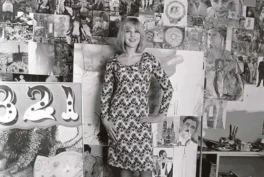 Photo of Pauline Boty in front of the wall with her collages.