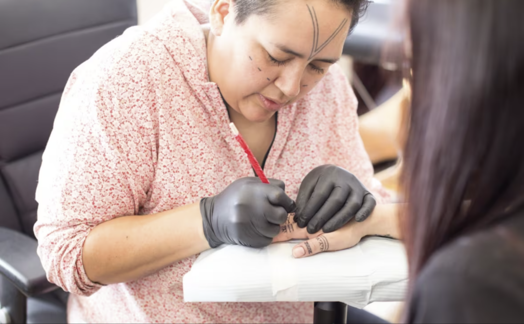 inuit art: Johnston tattoos a woman in Kugluktuk, ca. 2017. Photo by Cora DeVos/Little Inuk Photography. CBC News website.
