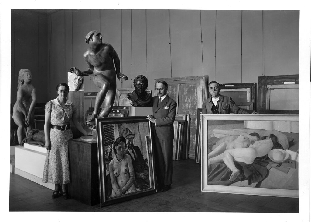 Rose Valland: Rose Valland, André Dézarrios and an attendant during the installation (or deinstallation) of the exhibition Italian art of Nineteenth and Twentieth Centuries at the Jeu de Paume Museum from May to July 1935. Photo: Archives nationales, France, 20144707/289 (box no. 1). Courtesy of Monuments Men and Women Foundation.
