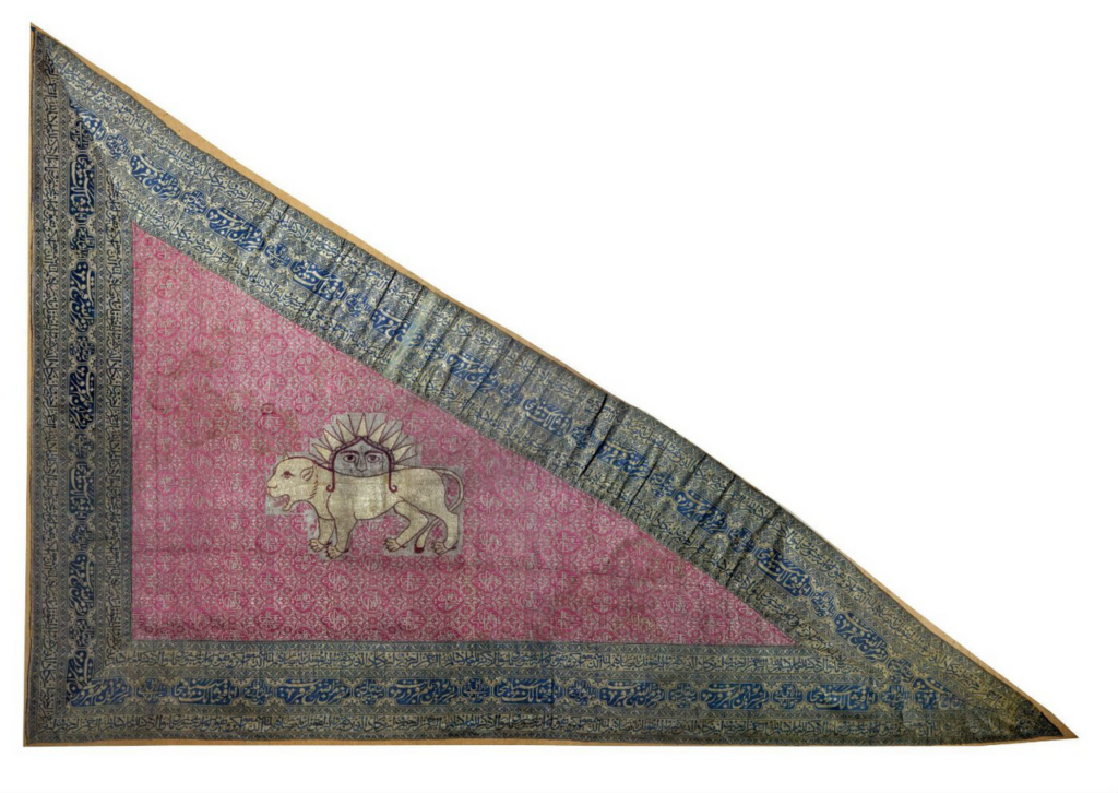 Lion and sun: Triangular silk flag of Iran, Qajar Dynasty, mid-19th Century. Photograph via Wikimedia Commons (public domain).
