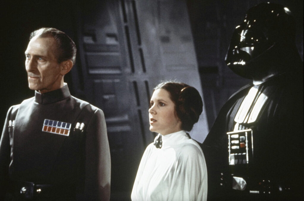 star wars propaganda art: Grand Moff Tarkin, Imperial officer, in the green-gray uniform, next to Princess Leia and Darth Vader. Movie still from Star Wars: Episode IV—A New Hope, directed by George Lucas, 1977. IMDb.
