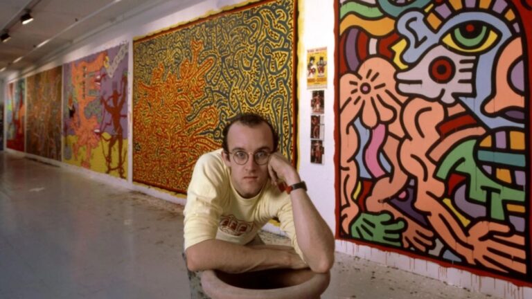 Keith Haring artworks: Photograph of Keith Haring in front of his paintings, c. 1985. Independent. Detail.
