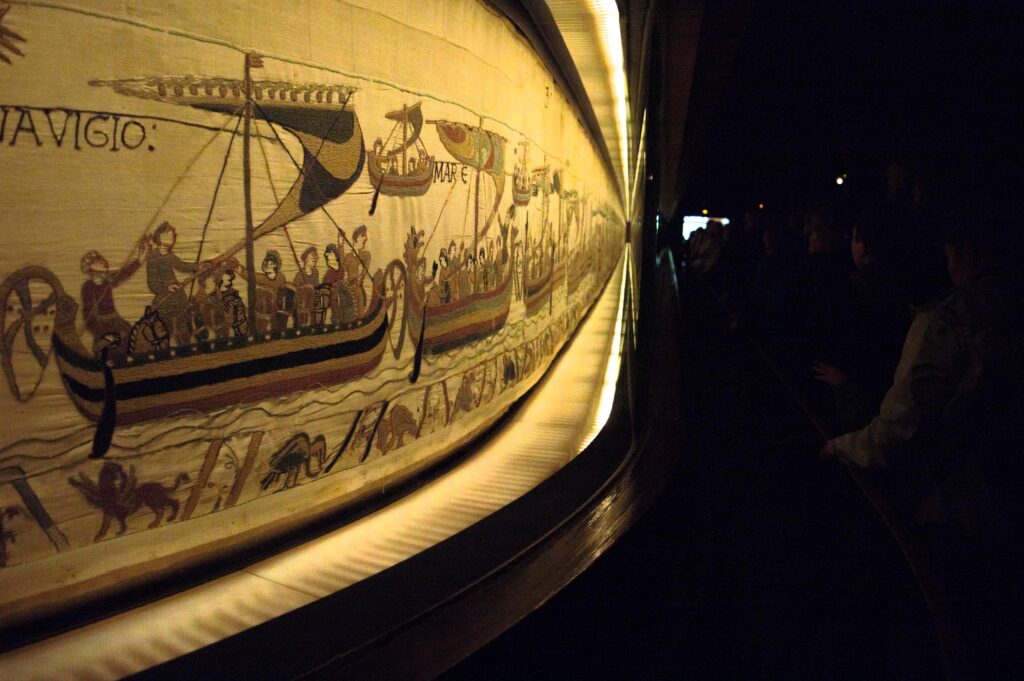 Bayeux Tapestry: Exhibition view of the Bayeux Tapestry, Musée de la Tapisserie de Bayeux, Bayeux, France. Photograph by Supercarwaar via Wikimedia Commons (CC BY-SA 4.0).
